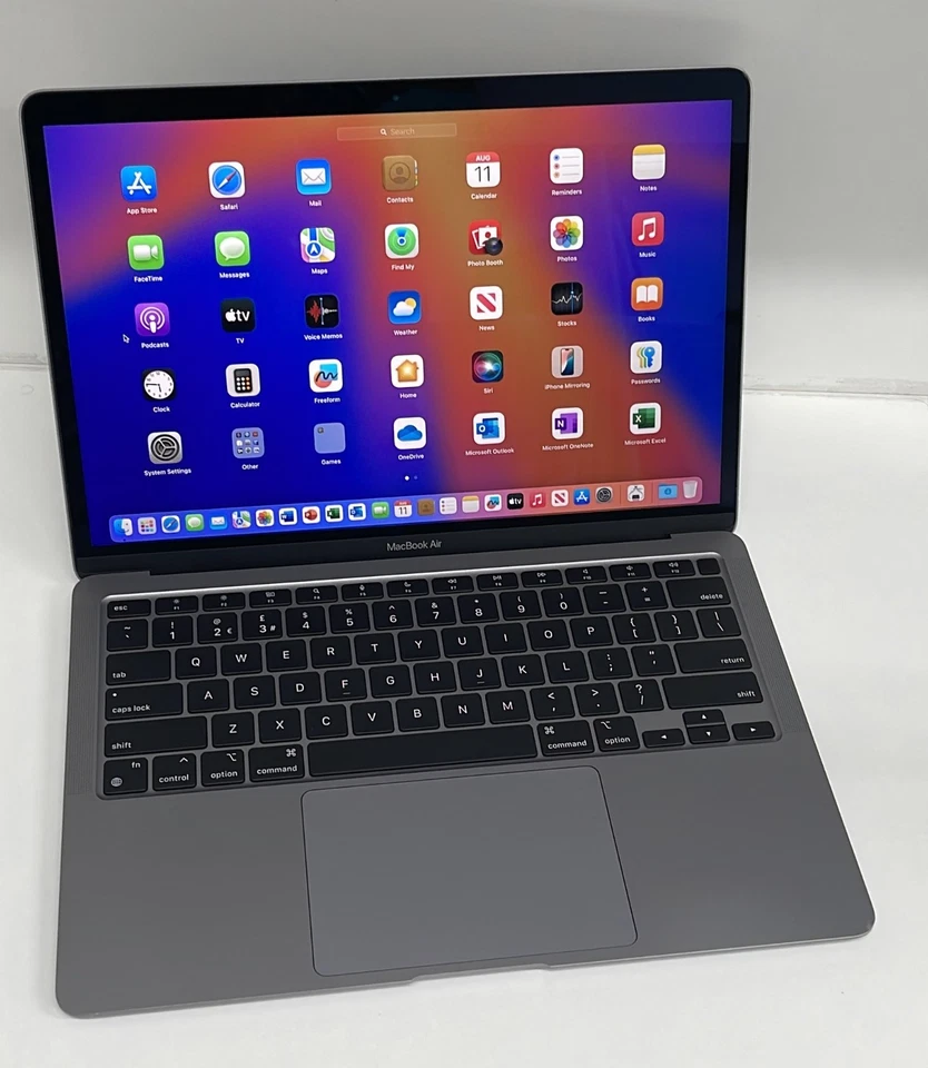 An Apple MacBook Air 2020 M1 (256GB, 16GB) in gray sits on a white surface with its screen open, displaying the iPadOS home screen full of app icons.